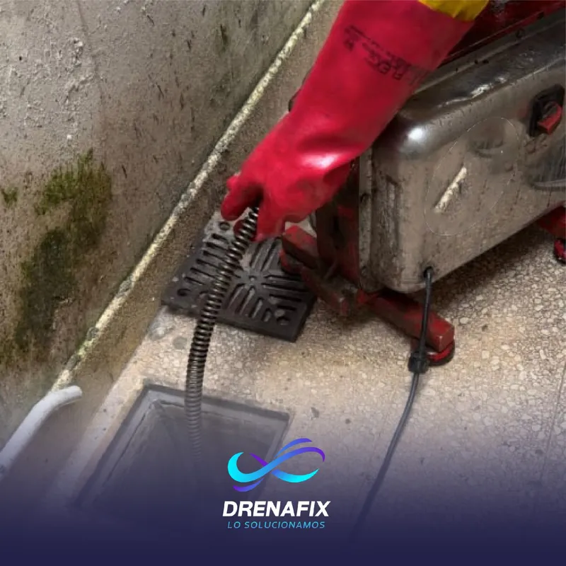Desobstrucción mecánica de desagüe con guantes rojos